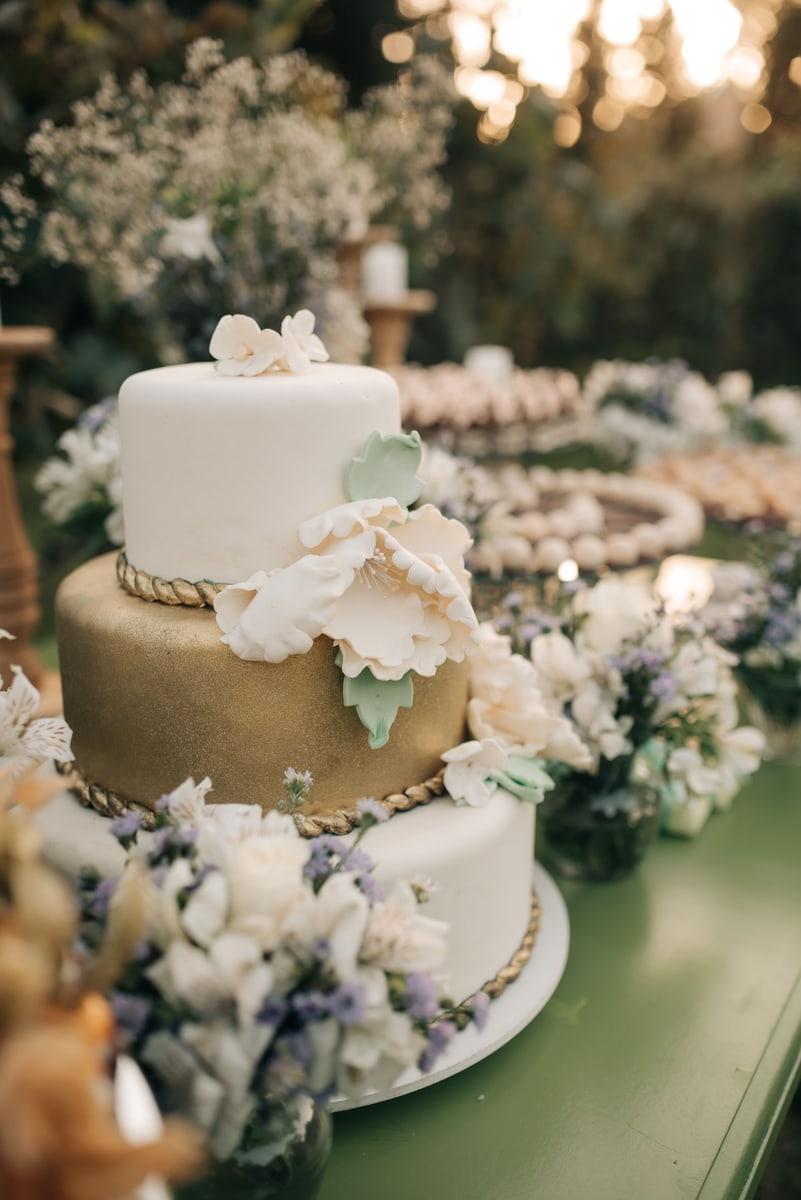 A white and gold wedding cake decorated with flowers