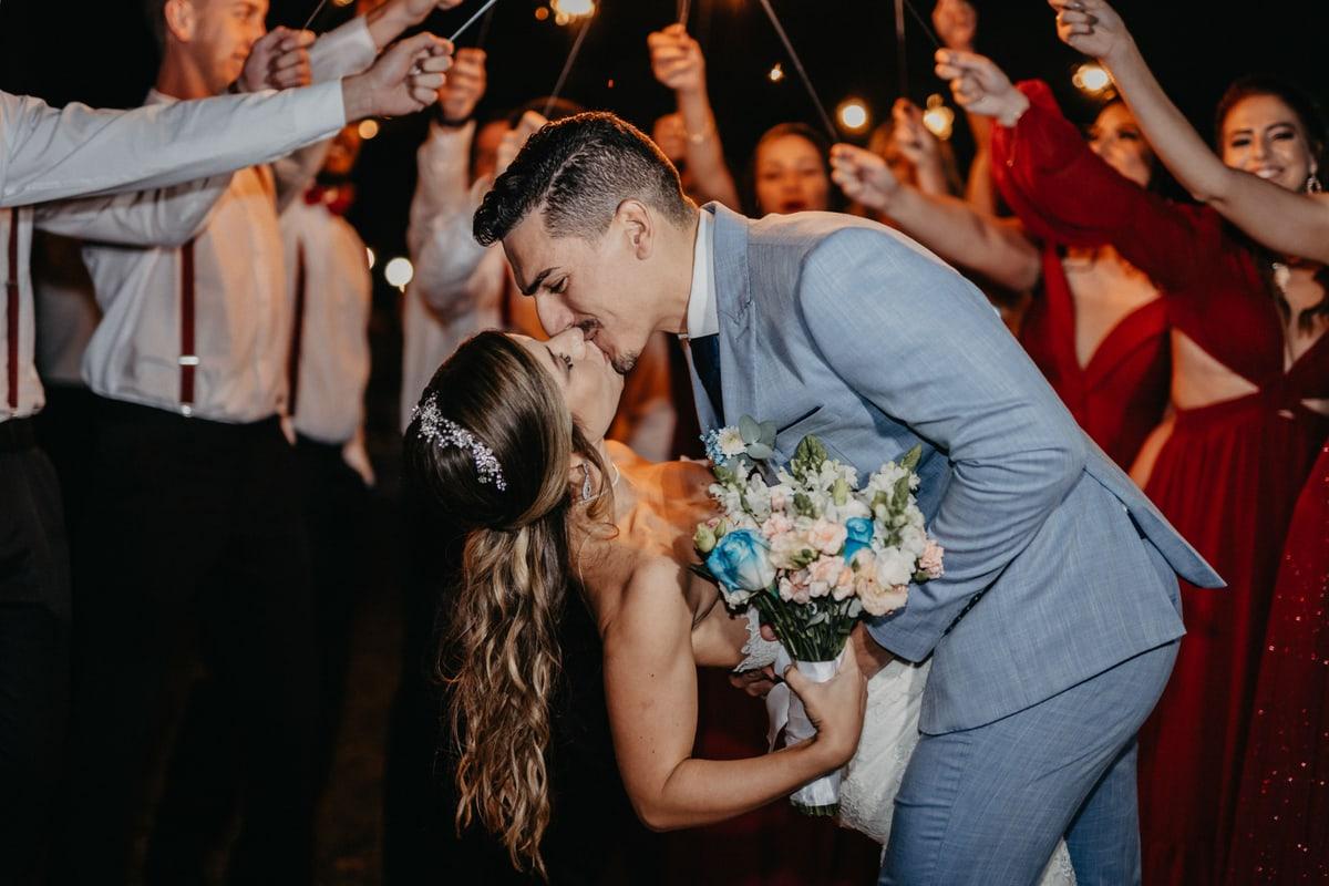 Newlyweds kissing as guests hold sparklers around them