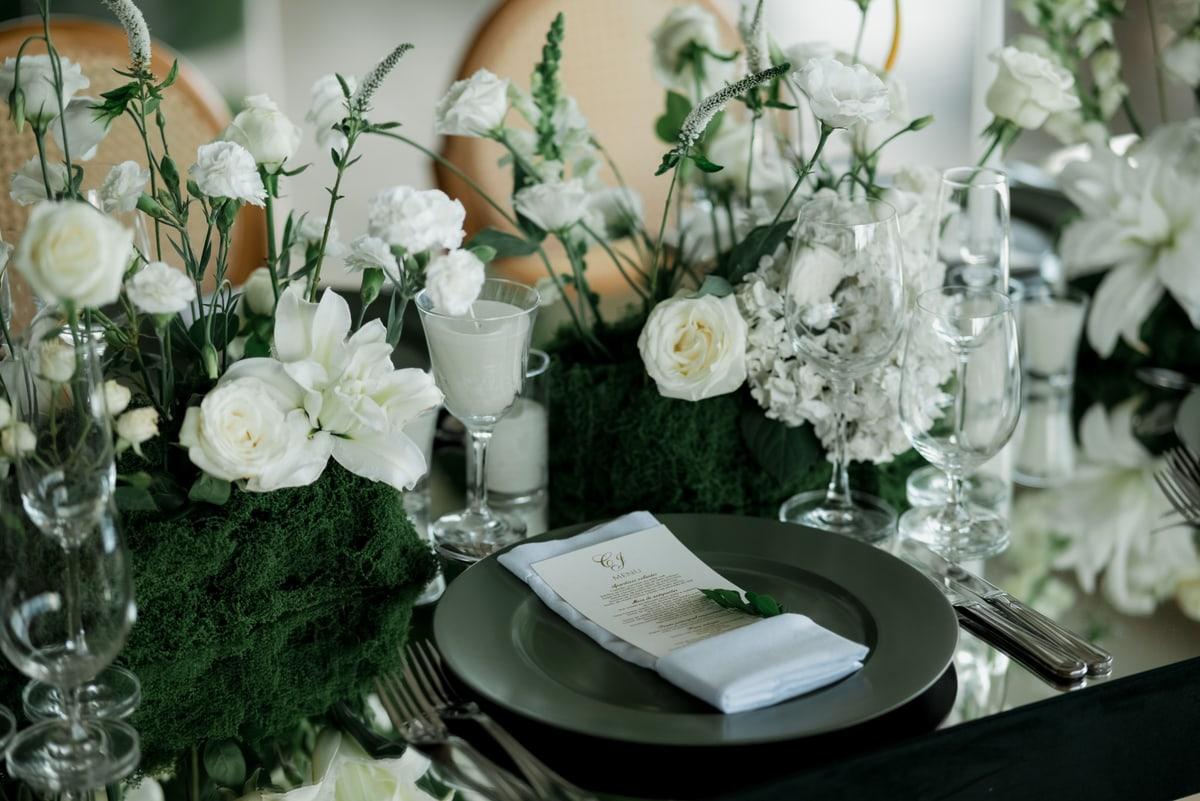 White flowers and glassware beside a wedding place setting